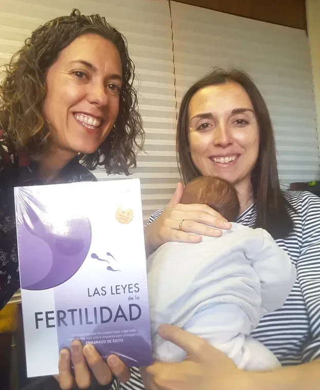 Mujer junto a una madre con su bebé y un libro sobre fertilidad