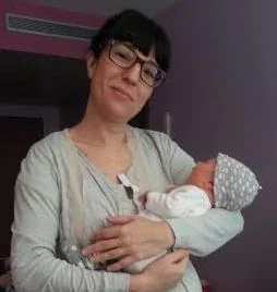 Madre con su bebé en brazos sonriendo a cámara